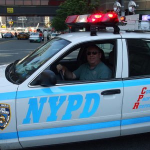 A photo of me sitting in an NYPD cruiser with Ground Zero in the background during NYPD musuem car show 2008. Approximately 40 to 50 vintage cars were